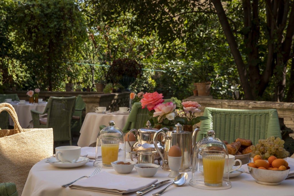 Historic French mansion turned luxury hotel with stone facade, ornate windows, and manicured garden courtyard in warm evening light