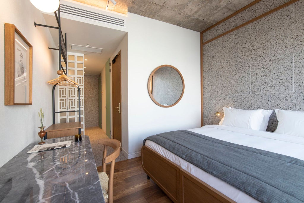 Minimalist hotel room with warm wood accents, crisp white linens, and modern design featuring soft lighting and elegant urban view of Athens cityscape