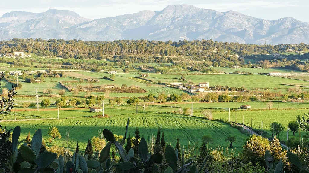 Luxurious Spanish countryside estate with stone walls, rustic wooden details, lush gardens, and panoramic Mediterranean scenery at a traditional Mallorcan agroturismo.