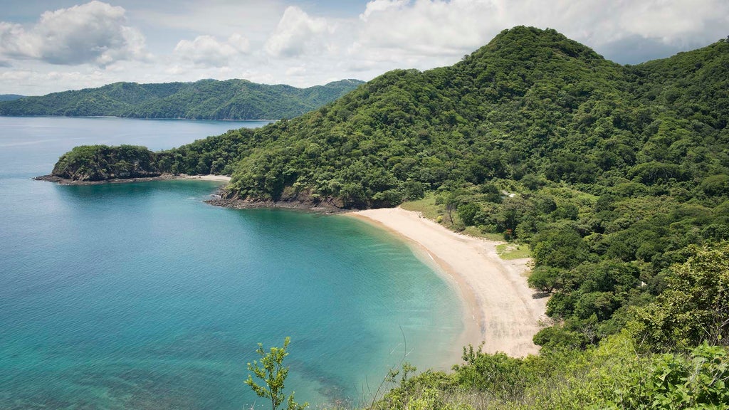 Elevated luxury tent suite overlooking Pacific Ocean waters, surrounded by lush Costa Rican jungle canopy at sunset