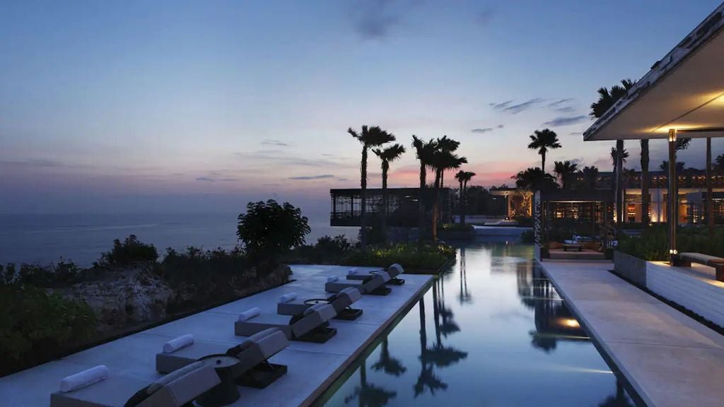 Luxurious infinity pool overlooking ocean cliffs at Alila Uluwatu, with modern cabanas and panoramic Bali coastline views at sunset