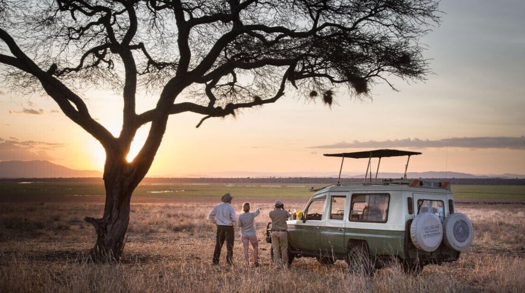 Luxurious African safari tent nestled in lush Tanzanian landscape, with elegant wooden furnishings and warm sunset light filtering through canvas panels