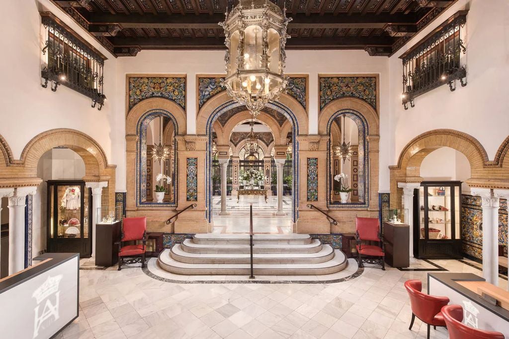 Ornate Moorish-style facade of Hotel Alfonso XIII with elegant arched windows, white columns and decorative tilework in warm sunlight