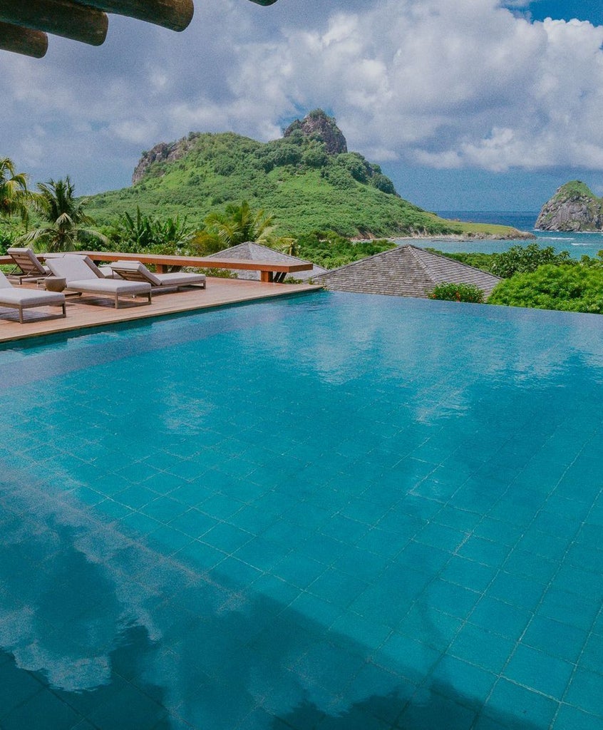 Luxurious white villa overlooking crystal-clear turquoise waters of Brazilian coastline, with modern minimalist architecture and private infinity pool