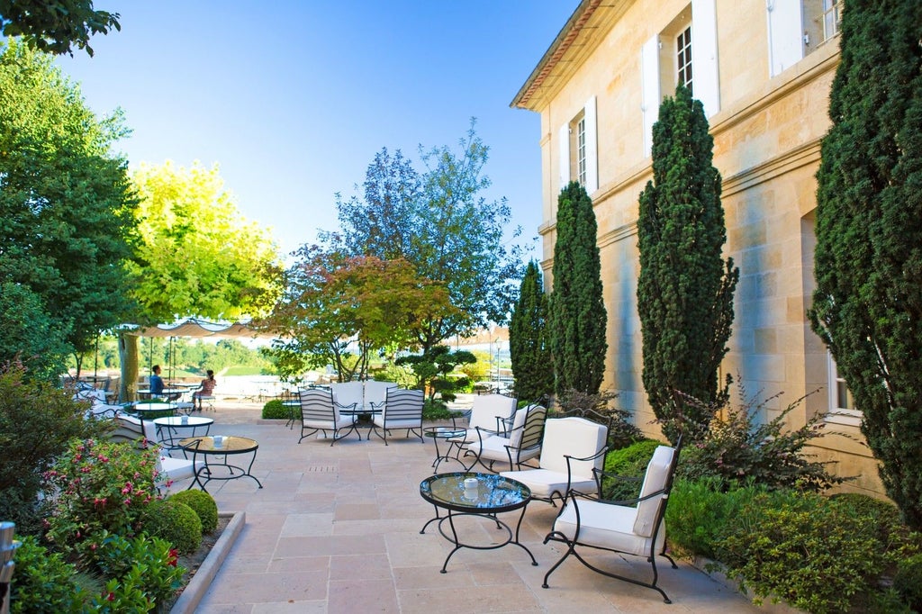 Historic French boutique hotel featuring elegant stone facade, arched windows, wrought-iron balconies and manicured courtyard garden