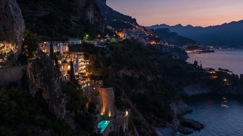 Stunning cliffside luxury hotel in Amalfi Coast with white terraces cascading down to private beach, Mediterranean sea views & elegant gardens