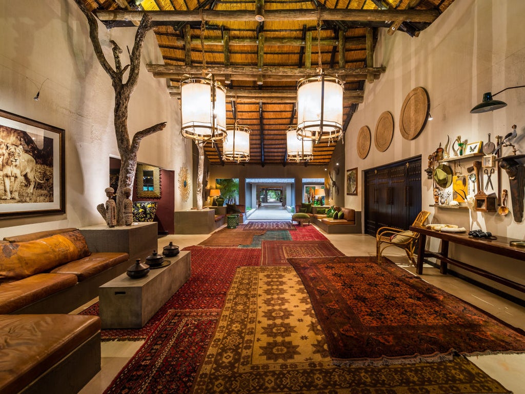 Luxurious safari lodge suite with private plunge pool overlooking African bush, featuring thatched roof and wooden deck terrace