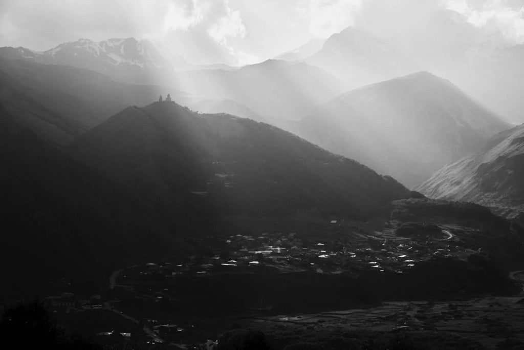 Luxurious mountain hotel room with panoramic views of Georgian alpine landscape, sleek modern design, and expansive windows revealing dramatic Kazbegi peaks