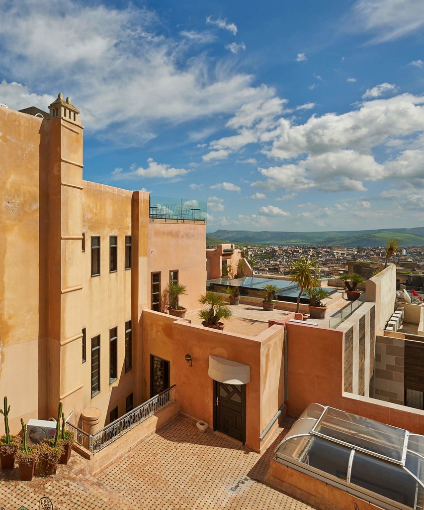 Elegant Moroccan riad with intricate blue and white zellige tiles, ornate archways, and a luxurious courtyard fountain in Fès medina