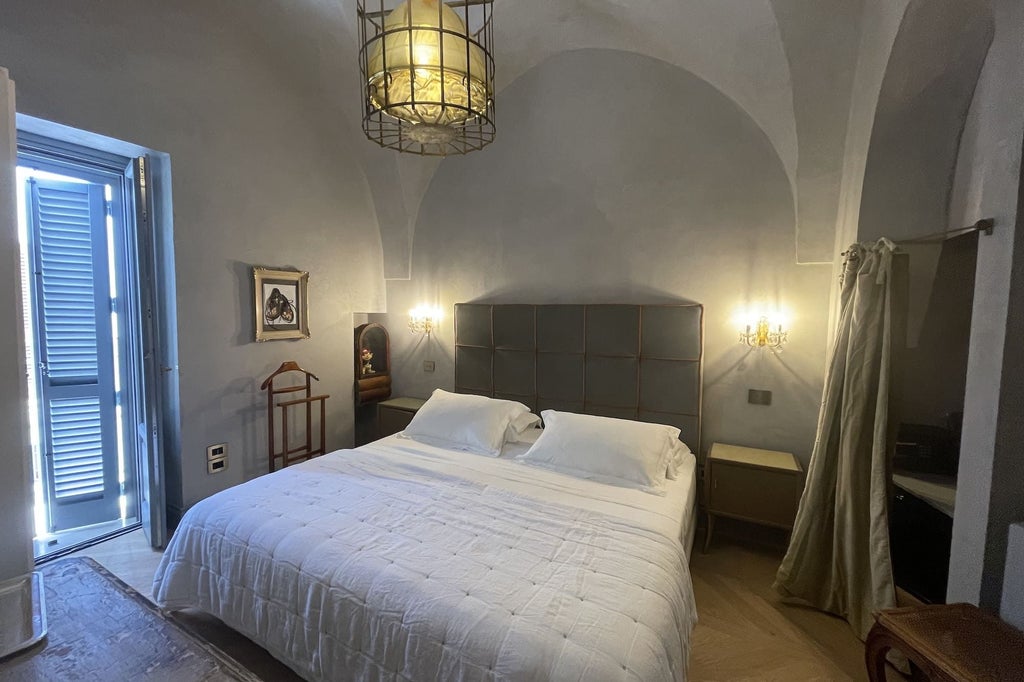 Elegant Deluxe Room at Boutique Hotel with rich terracotta walls, plush white bedding, and vintage Baroque-inspired furnishings in scenic Italian setting