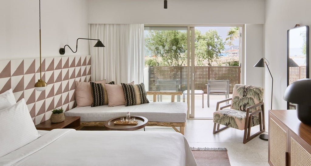 Luxurious bungalow room with side sea view at Phāea Cretan resort, featuring modern decor, plush bedding, and a glimpse of azure Aegean waters through large windows