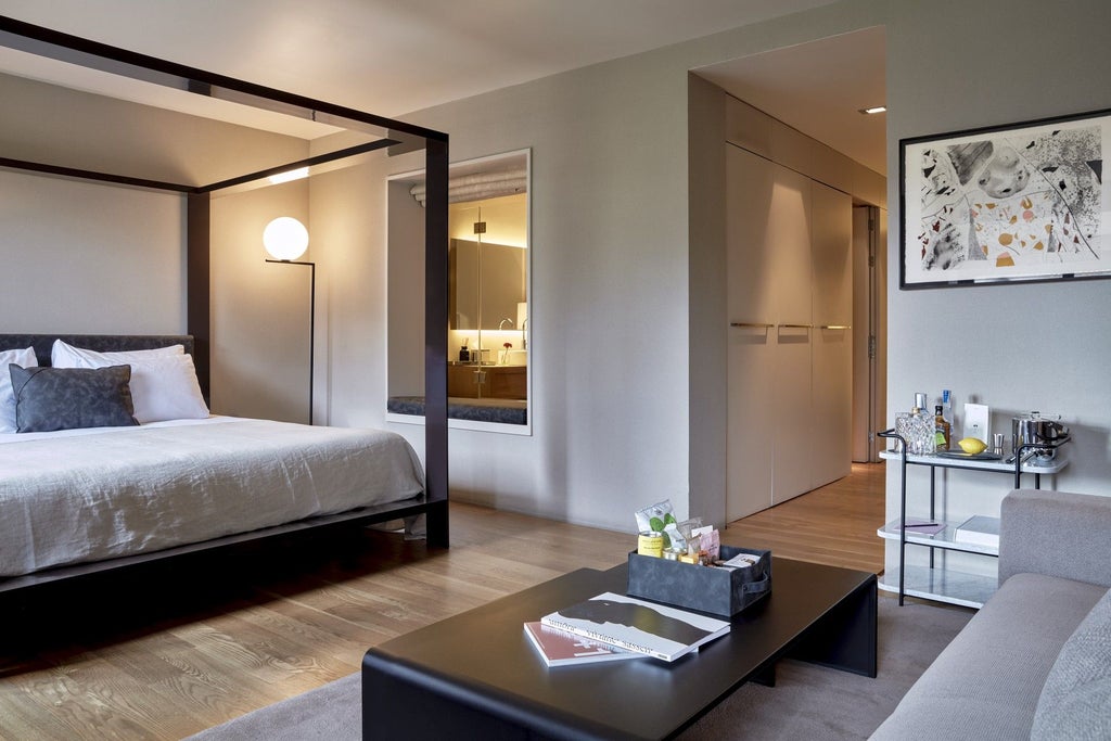 Elegant modern hotel room with sleek minimalist design, large floor-to-ceiling windows, neutral color palette, and contemporary luxury furnishings in Barcelona