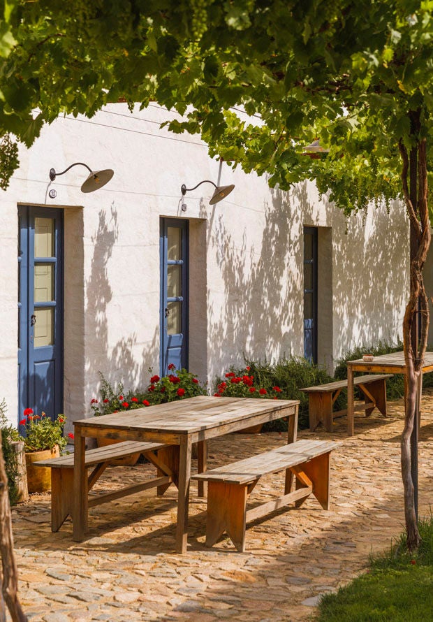 Elegant white-walled Portuguese farmhouse hotel with stone arches, rustic wooden doors and terracotta roof amid peaceful countryside scenery