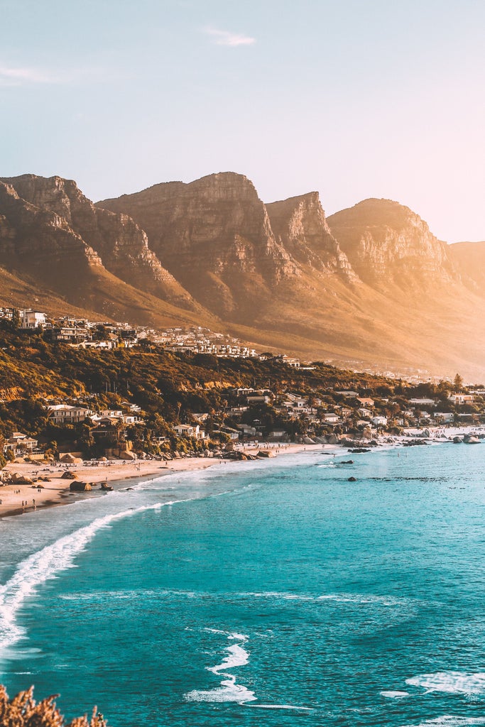 Rugged coastline view at Cape Peninsula with luxury SUV parked near scenic lookout point, dramatic cliffs meeting turquoise waters