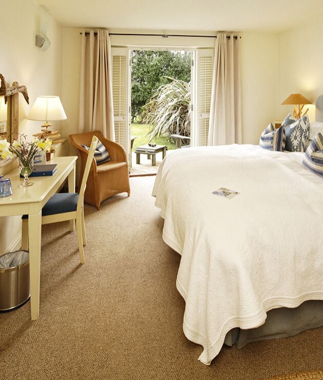 Elegant coastal hotel room with panoramic sea view, wooden furnishings, crisp white linens, and blue accents reflecting maritime UK hospitality design