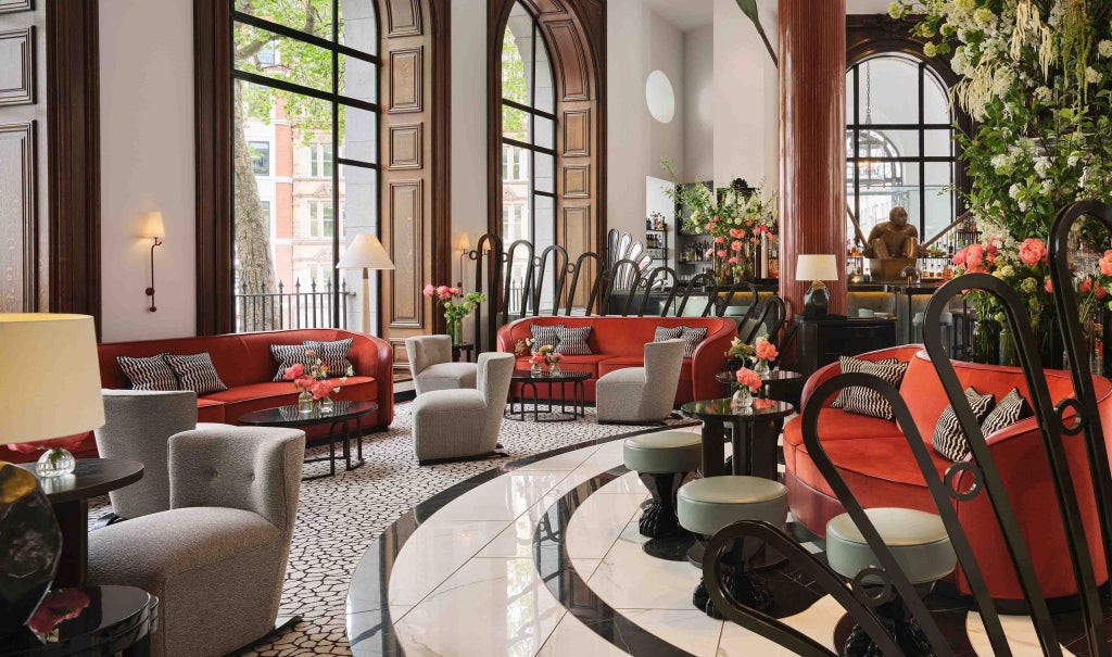 Luxurious lobby of boutique hotel with elegant contemporary design, marble columns, soft lighting, and chic seating area in London's prestigious location