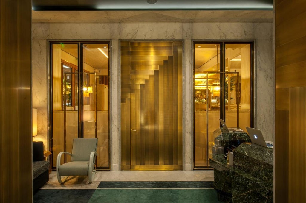 Grand marble staircase with ornate gold railings in Nolinski Paris hotel lobby, featuring dramatic lighting and neoclassical architecture