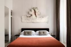 Elegant modern hotel room with soft neutral tones, plush white bedding, minimalist decor, large window overlooking roman architecture near scenset Square