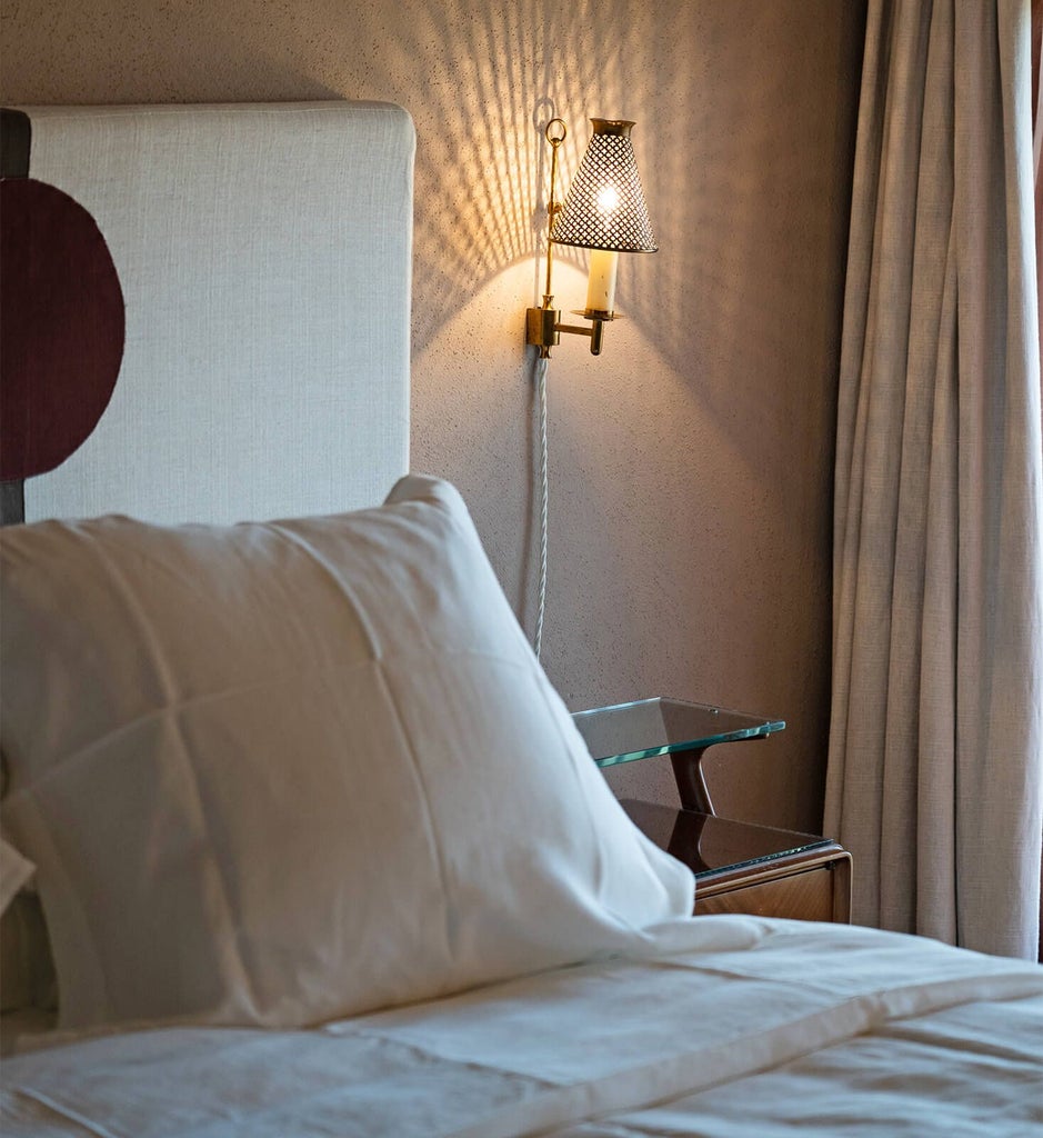 Elegant Tuscan-style bedroom with white linen, rustic wooden furniture, soft natural light, and panoramic countryside view near Lucca