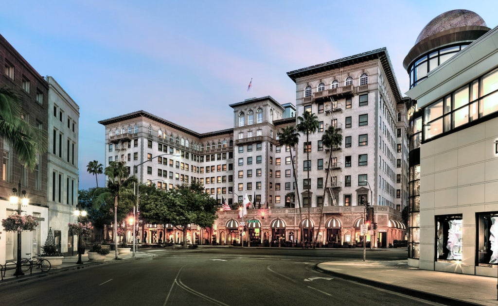 Iconic Four Seasons Beverly Wilshire hotel's beige facade with ornate European architecture, elegant archways and palm trees in Beverly Hills