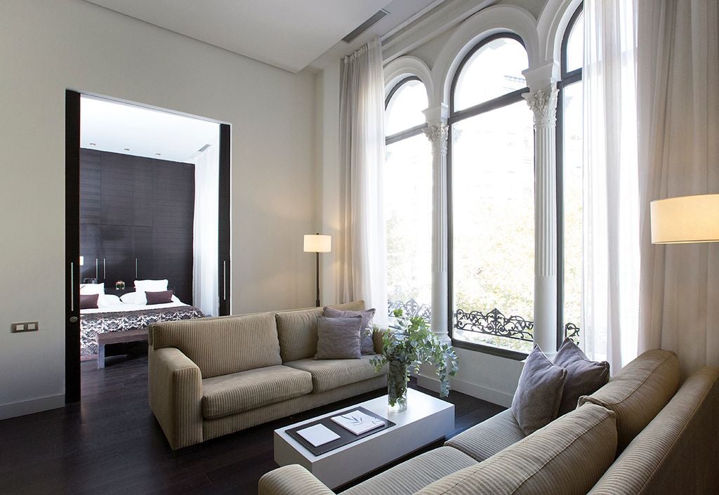 Elegant presidential suite in Valencia, Spain, featuring plush white bedding, modern minimalist design, and luxurious marble bathroom with city view