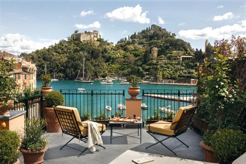 Opulent beachfront hotel with marble columns, overlooking the Mediterranean Sea at sunset, featuring a grand terraced balcony and palm trees