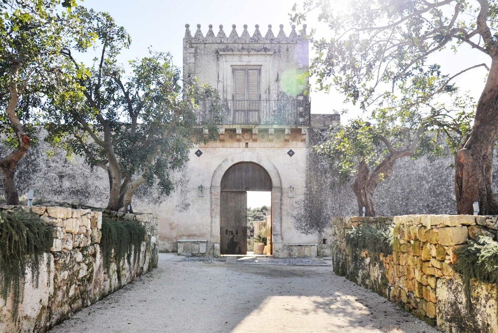 Elegant Italian boutique hotel with stone archways and terrace seating overlooking rolling countryside at golden hour