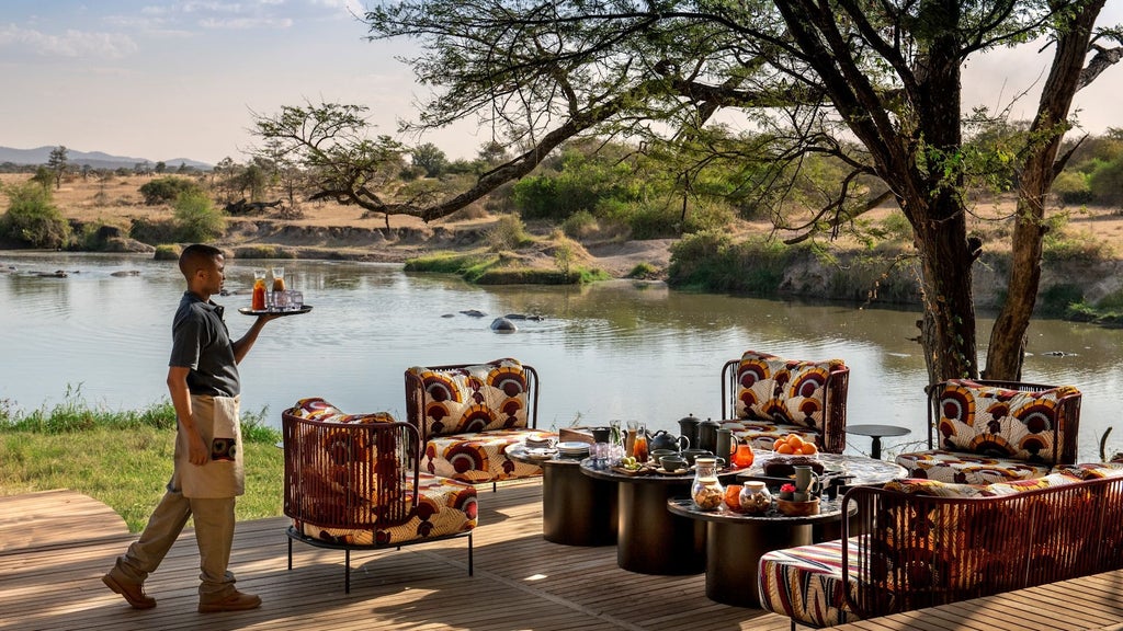 Open-air villa with infinity pool overlooking Serengeti savanna, featuring modern thatched roof and luxurious outdoor lounge area