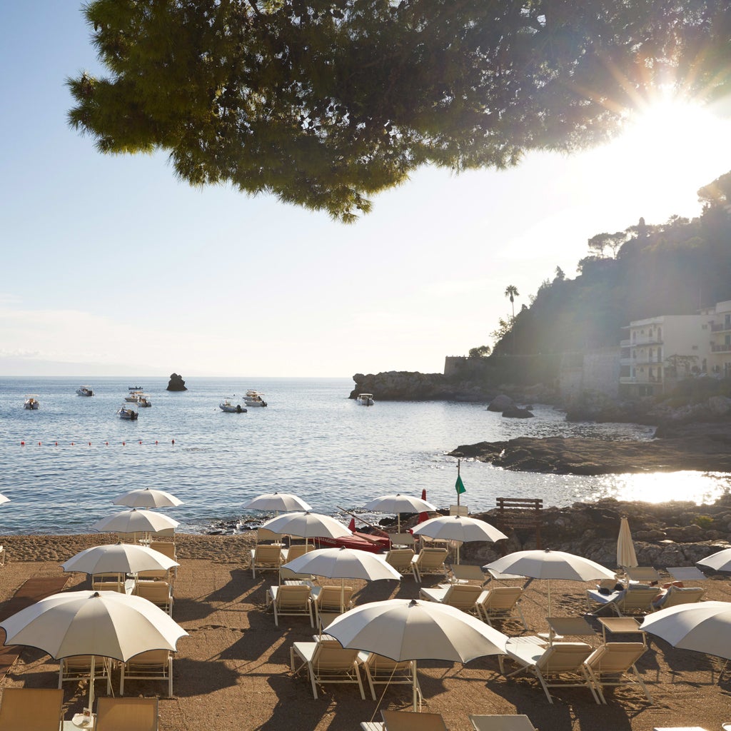 Elegant seaside hotel with private beach, infinity pool overlooking Bay of Mazzarò, and classic Italian architecture in Taormina