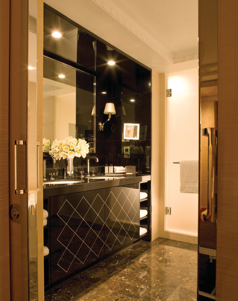 Elegant brick facade of luxury hotel with arched windows, polished brass entrance doors, and manicured hedges along Park Lane, London