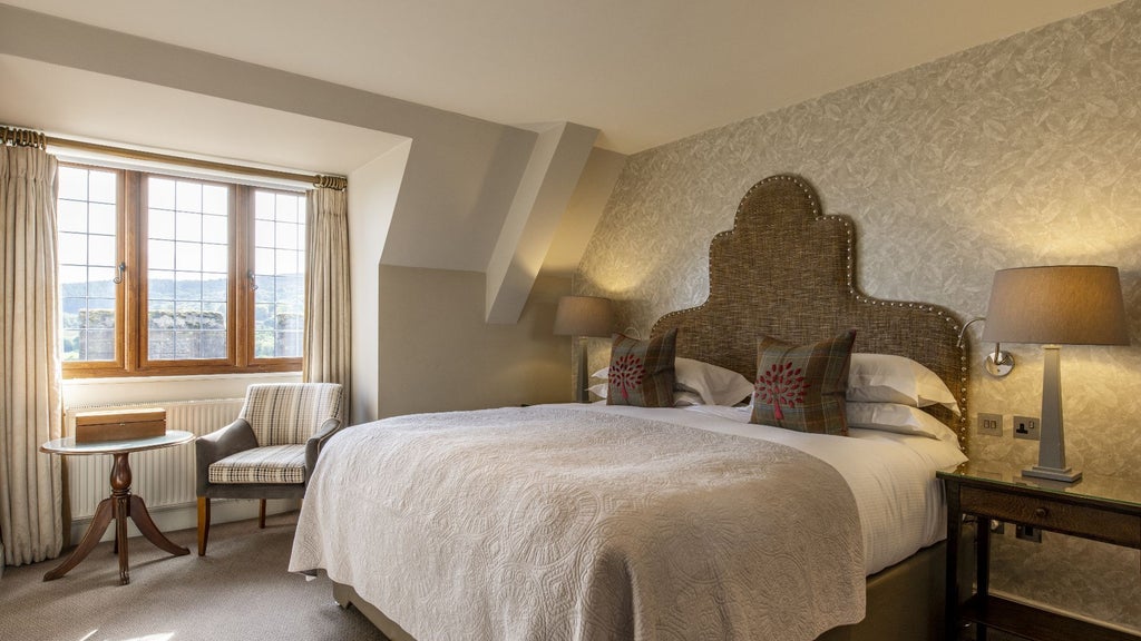 Elegant classic-style hotel room with plush furnishings, cream and navy color palette, ornate wooden furniture at luxury Bovey Castle Hotel in scenic Devon, United Kingdom