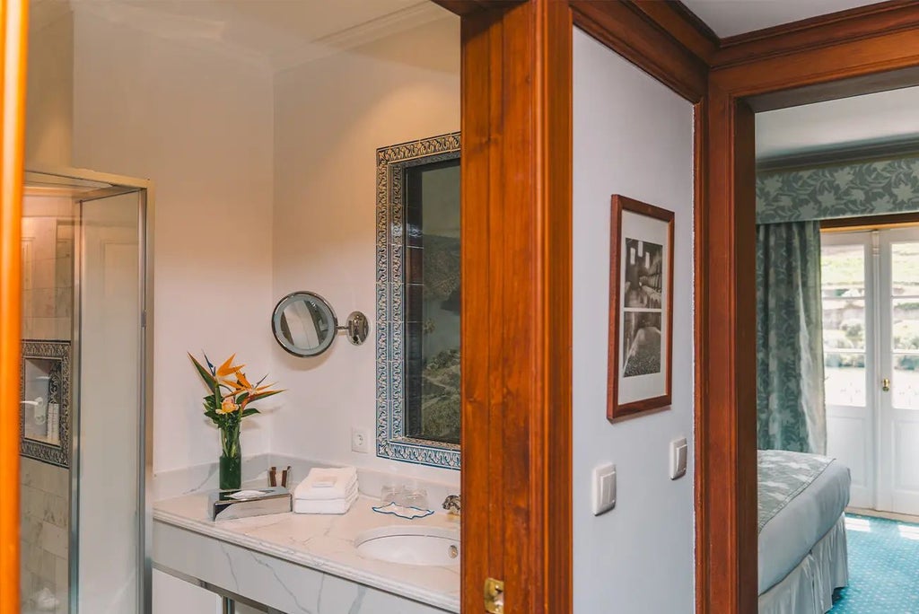 Elegant vintage-inspired hotel room with warm wooden furnishings, plush white bedding, and soft neutral tones in a charming Portuguese setting