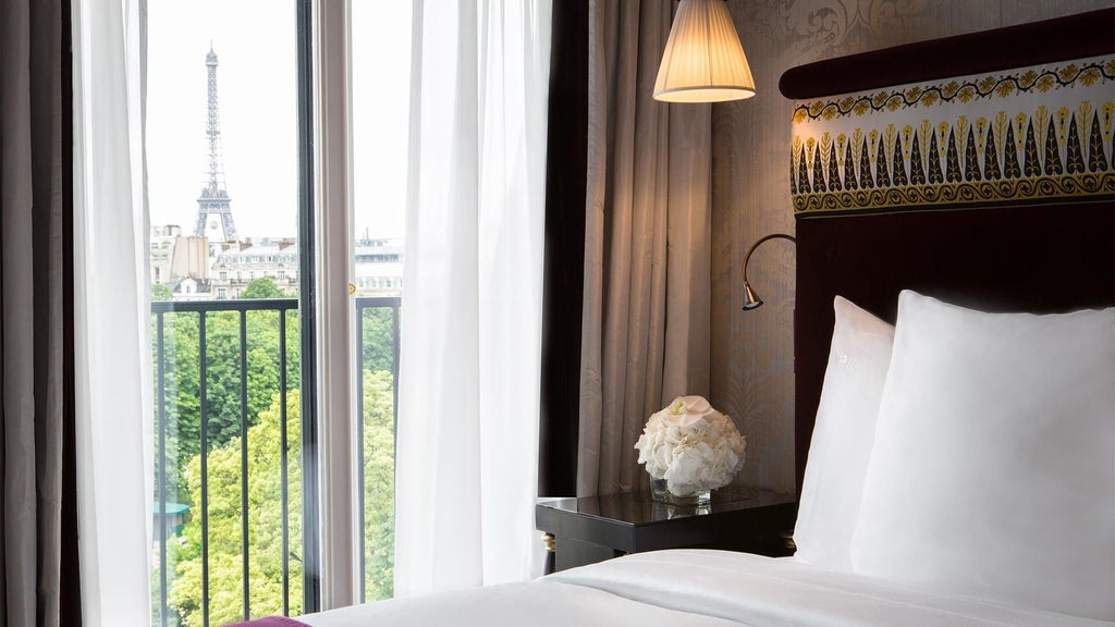 Elegant Parisian luxury junior suite with plush cream furnishings, soft lighting, and panoramic view of iconic Eiffel Tower through expansive windows