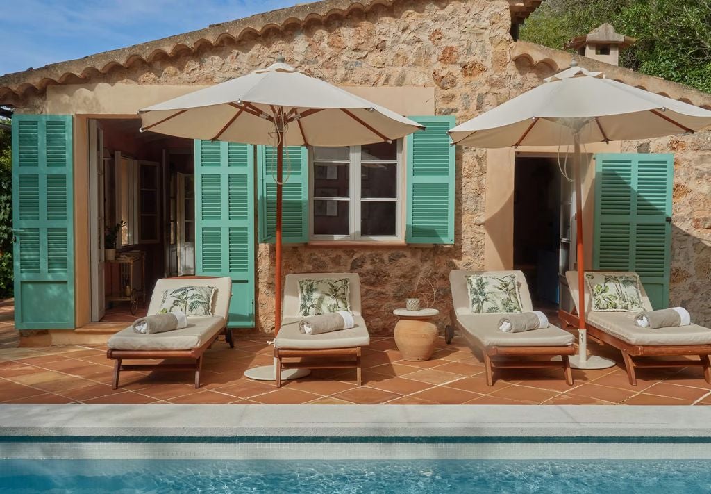 Vibrant Mediterranean-inspired luxury suite with bold floral patterns, elegant furnishings, and a private terrace overlooking Mallorca's mountains