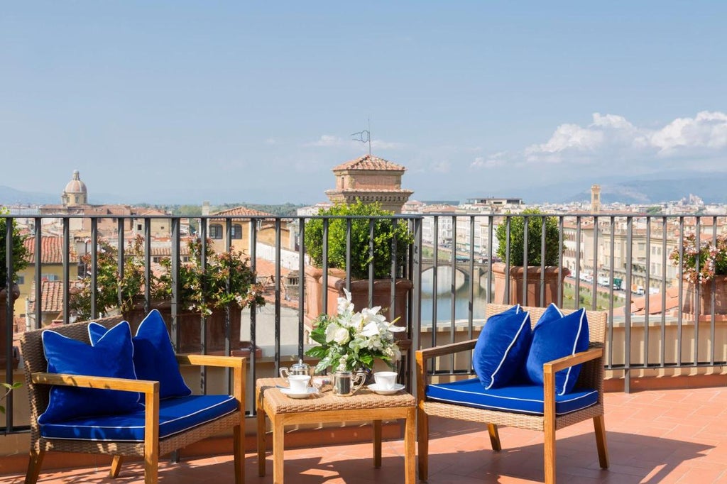 Five-star Hotel Lungarno perched along Arno River in Florence, featuring elegant white facade with blue awnings and riverside terrace dining