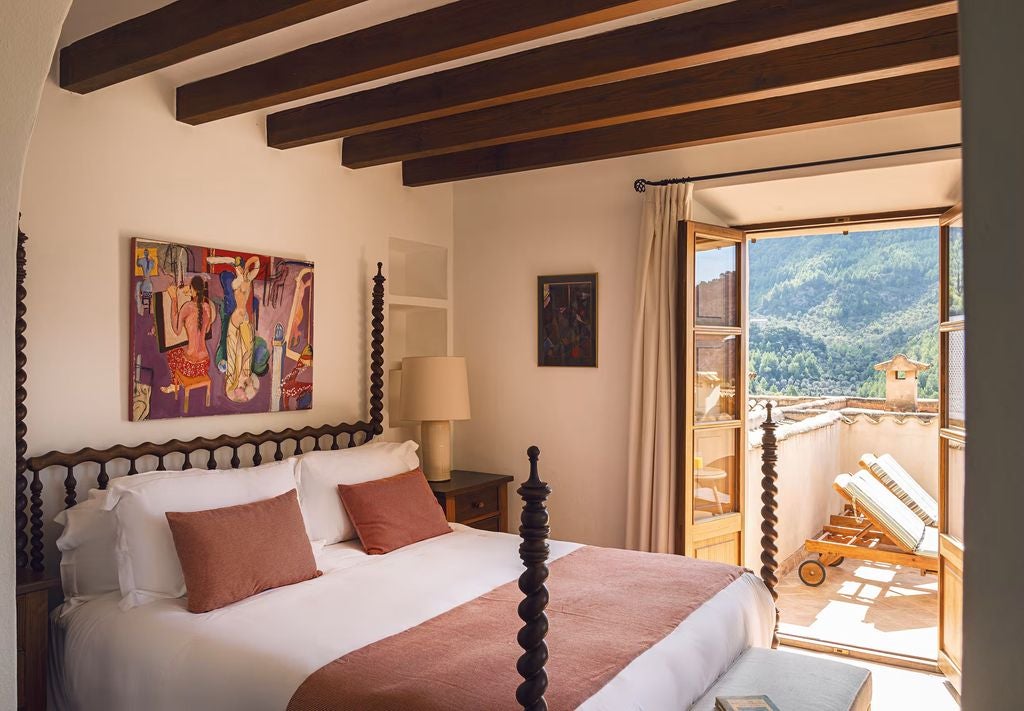 Elegant Superior Junior Suite featuring a four-poster bed, terracotta floors, and French doors opening to a private terrace with mountain views