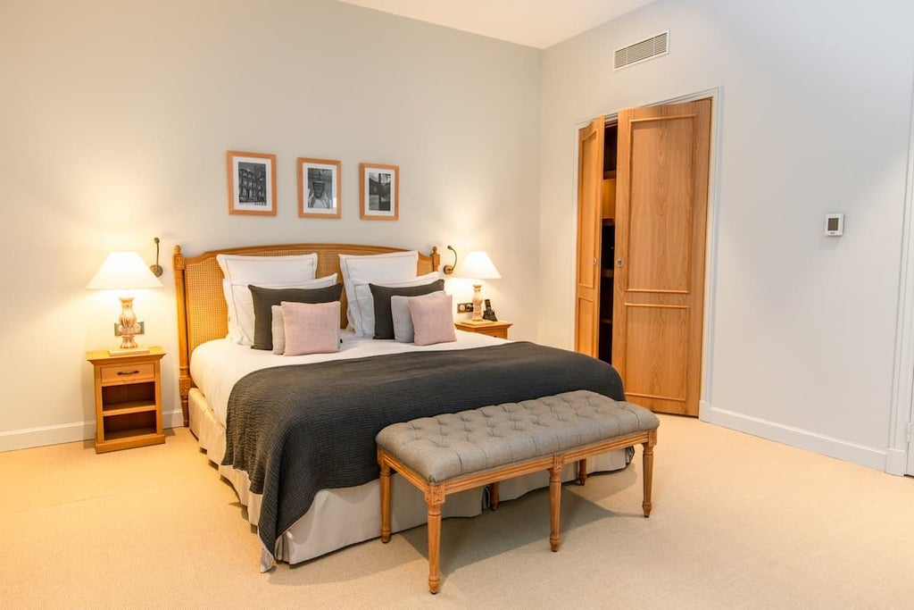 Elegant premier hotel room with plush white bedding, soft neutral tones, wooden floor, and contemporary French design in Cognac's Chais Monnet boutique hotel