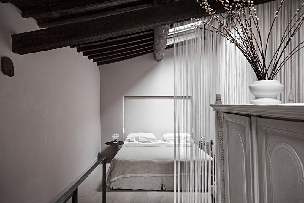 Minimalist Italian loft with exposed wood beams, modern furniture, and large windows overlooking Tuscan landscape in soft morning light.