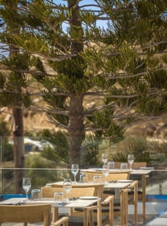 Luxurious white-washed hotel overlooking azure Aegean Sea, with minimalist Greek architecture, infinity pool, and stunning Mykonos landscape backdrop