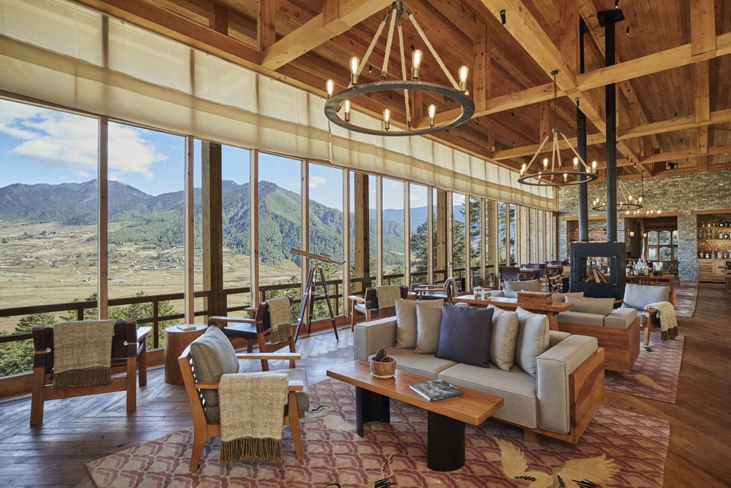 Elegant wooden lodge with floor-to-ceiling windows perched on Bhutanese hillside, overlooking misty valley and snow-capped mountains