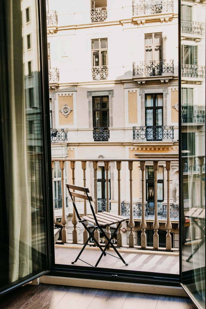 Elegant boutique hotel facade in Barcelona's Gothic Quarter, blending historic architecture with modern design, warm sunlight on stone walls and ornate balconies