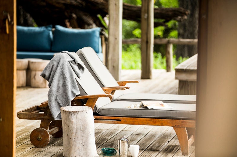 Elevated luxury safari lodge with wooden deck overlooking vast Okavango Delta plains, featuring private plunge pool and lounge seating