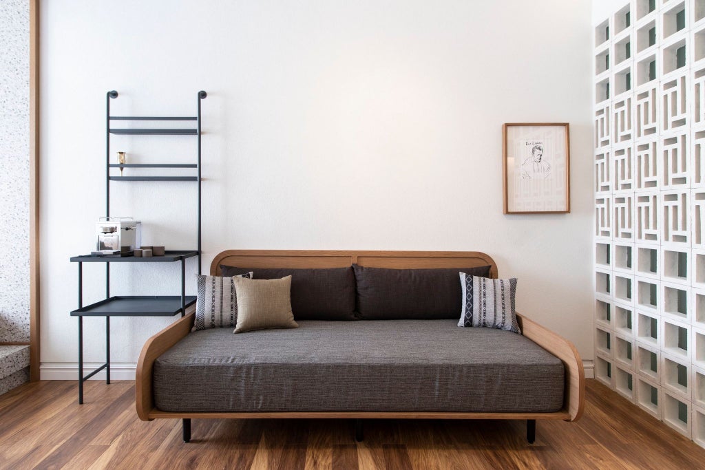 Spacious Athens hotel room with minimalist design, high ceilings, warm wood furnishings, and large windows overlooking urban landscape in Ergon House.