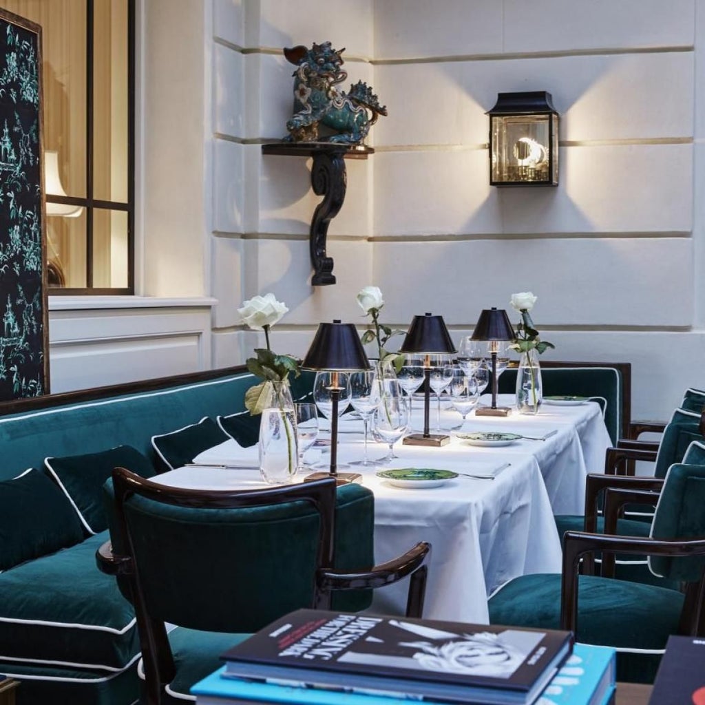 Elegant ivory facade of luxurious Parisian boutique hotel with ornate windows, classic French architectural details, and chic exterior lighting at dusk