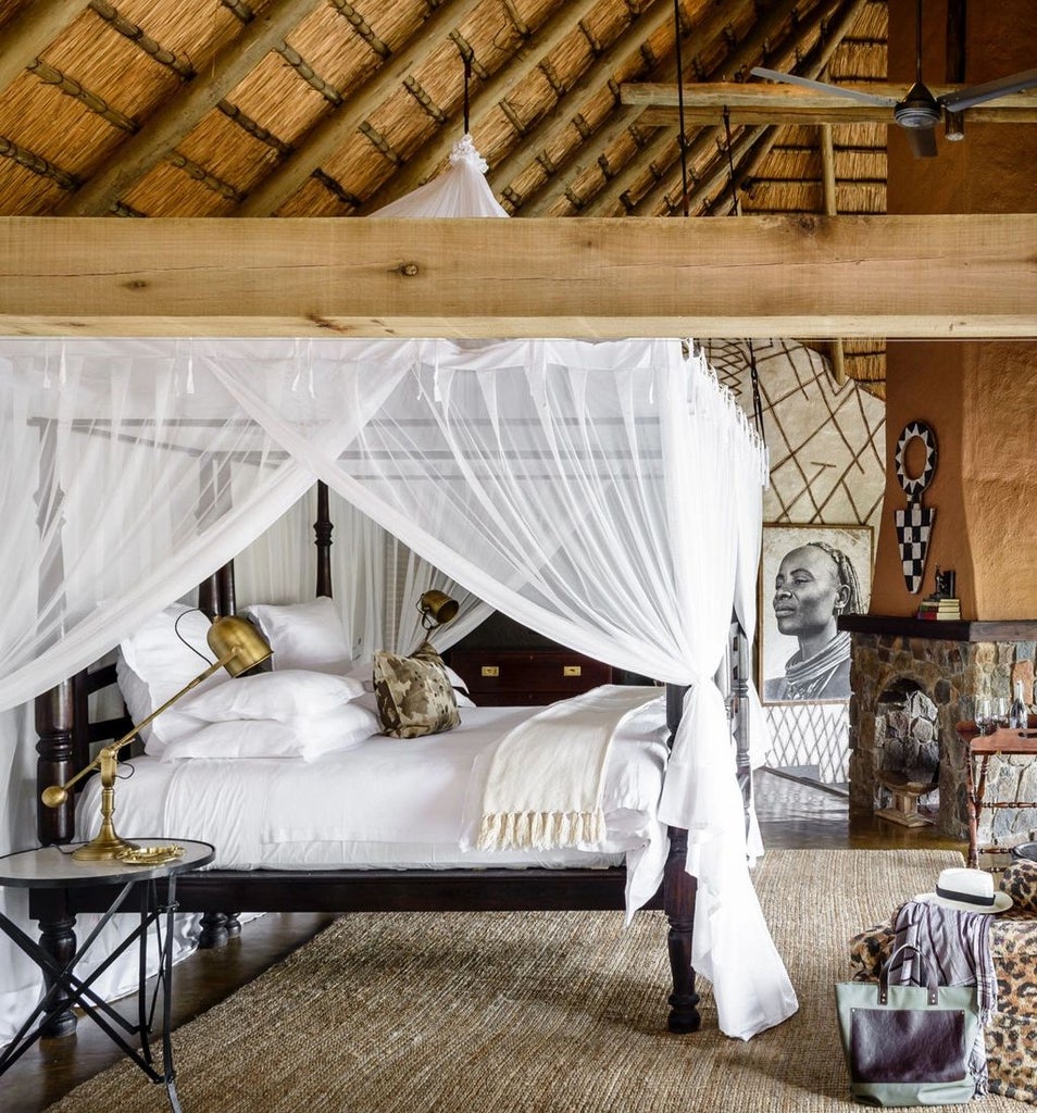 Safari lodge suite with private plunge pool overlooking African savanna, featuring thatched roof and floor-to-ceiling glass doors