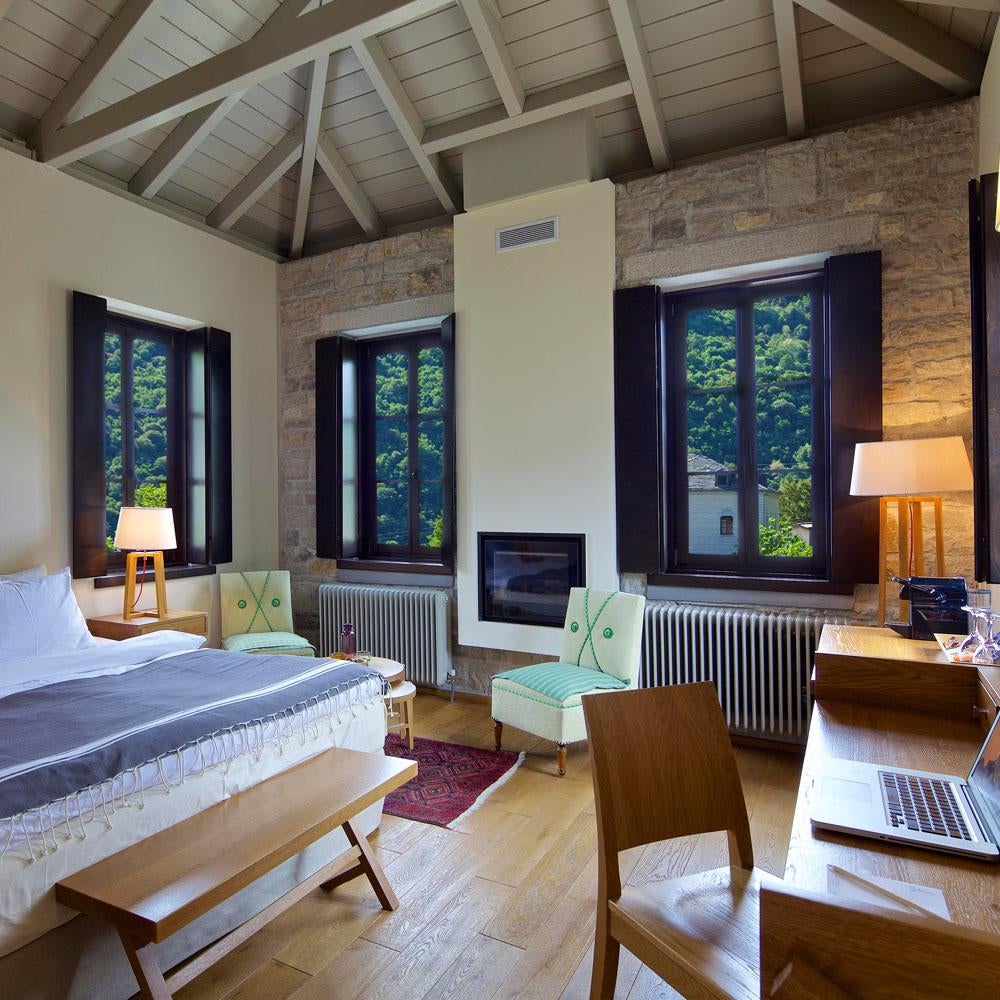 Elegant mountain lodge with stone walls and wooden balconies nestled in misty Greek peaks, surrounded by lush forest at sunrise