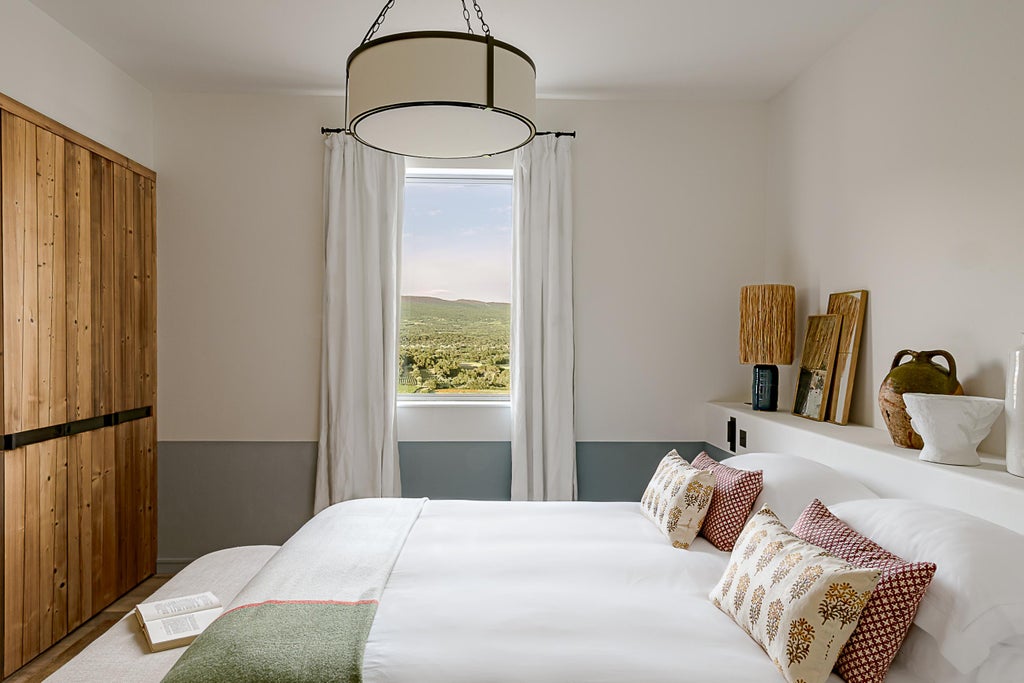 Elegant suite with exposed stone walls, crisp white bedding, and French doors opening to mountain views of Mont Ventoux in Provence