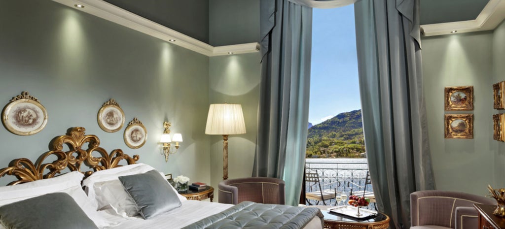 Elegant lakeside Italian hotel with Art Nouveau facade, featuring opulent terraces overlooking Lake Como and snow-capped mountains beyond