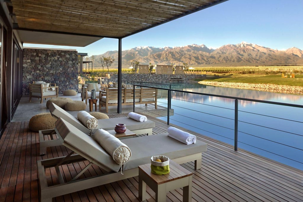 Luxurious Andean hotel suite with floor-to-ceiling windows overlooking vineyards and snow-capped mountains in Mendoza, Argentina