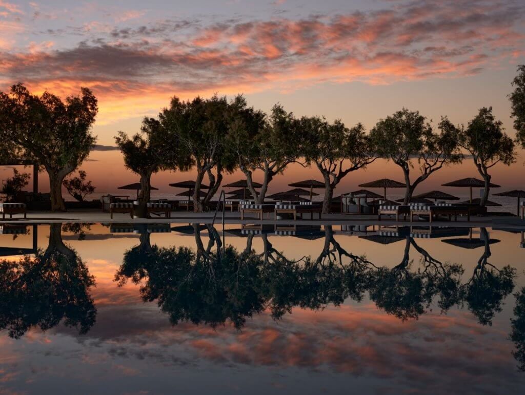 Luxurious beachfront resort with modern architecture, crystal-clear Aegean waters, and sleek minimalist design at a scenic Cretan coastal location.